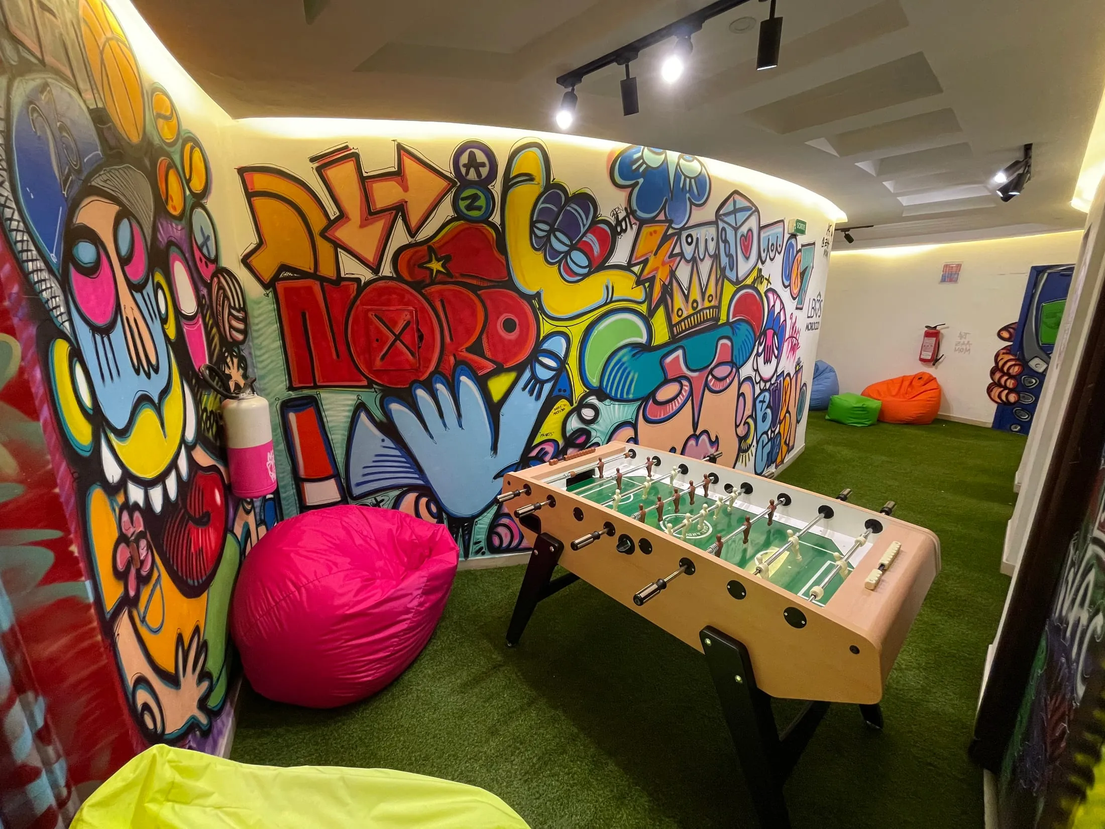 Games room covered in colorful cartoon graffiti characters with a foosball table in the middle