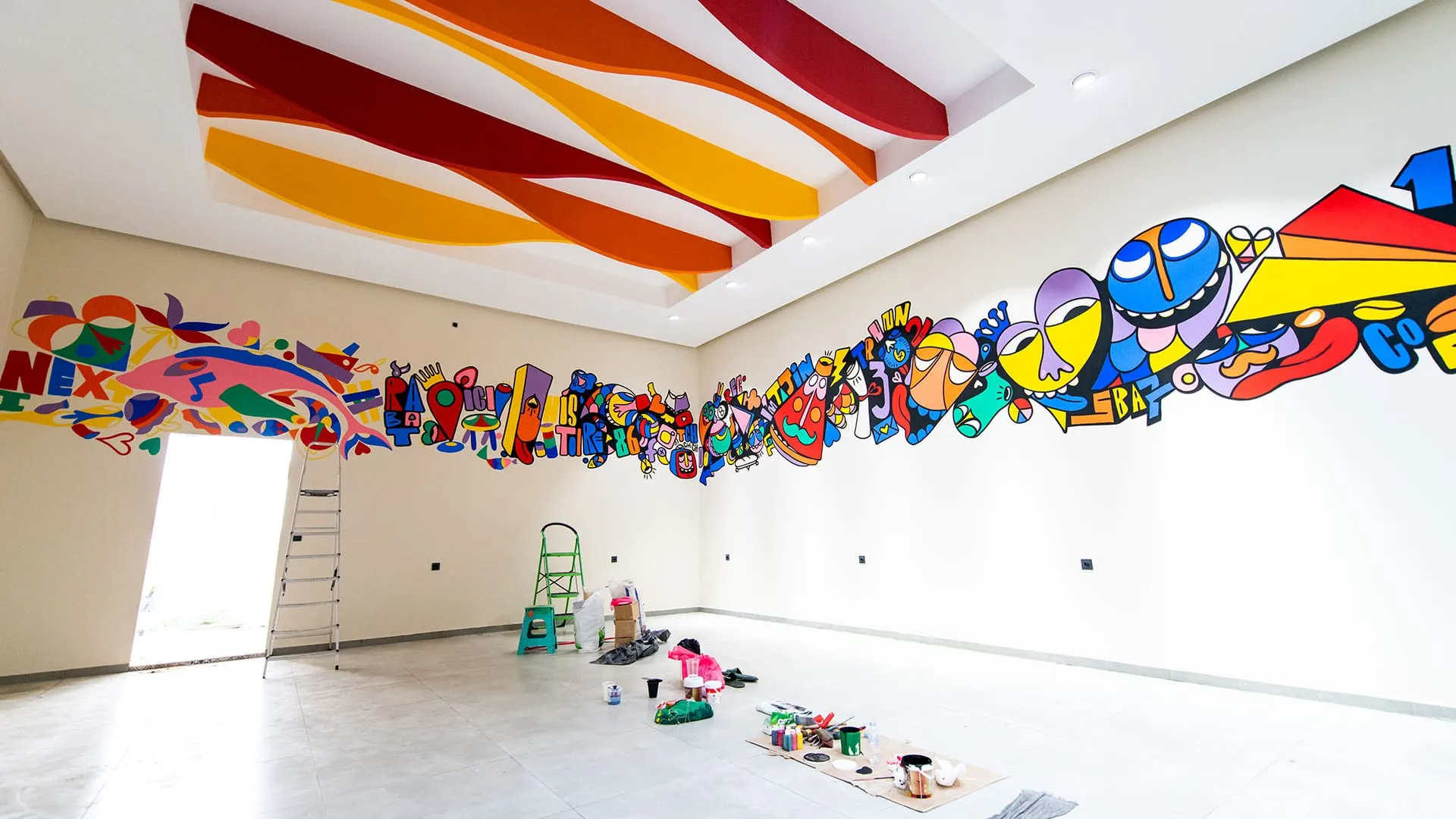 Colorful pop-art mural frieze wrapping a bright hall with painted waves on the ceiling