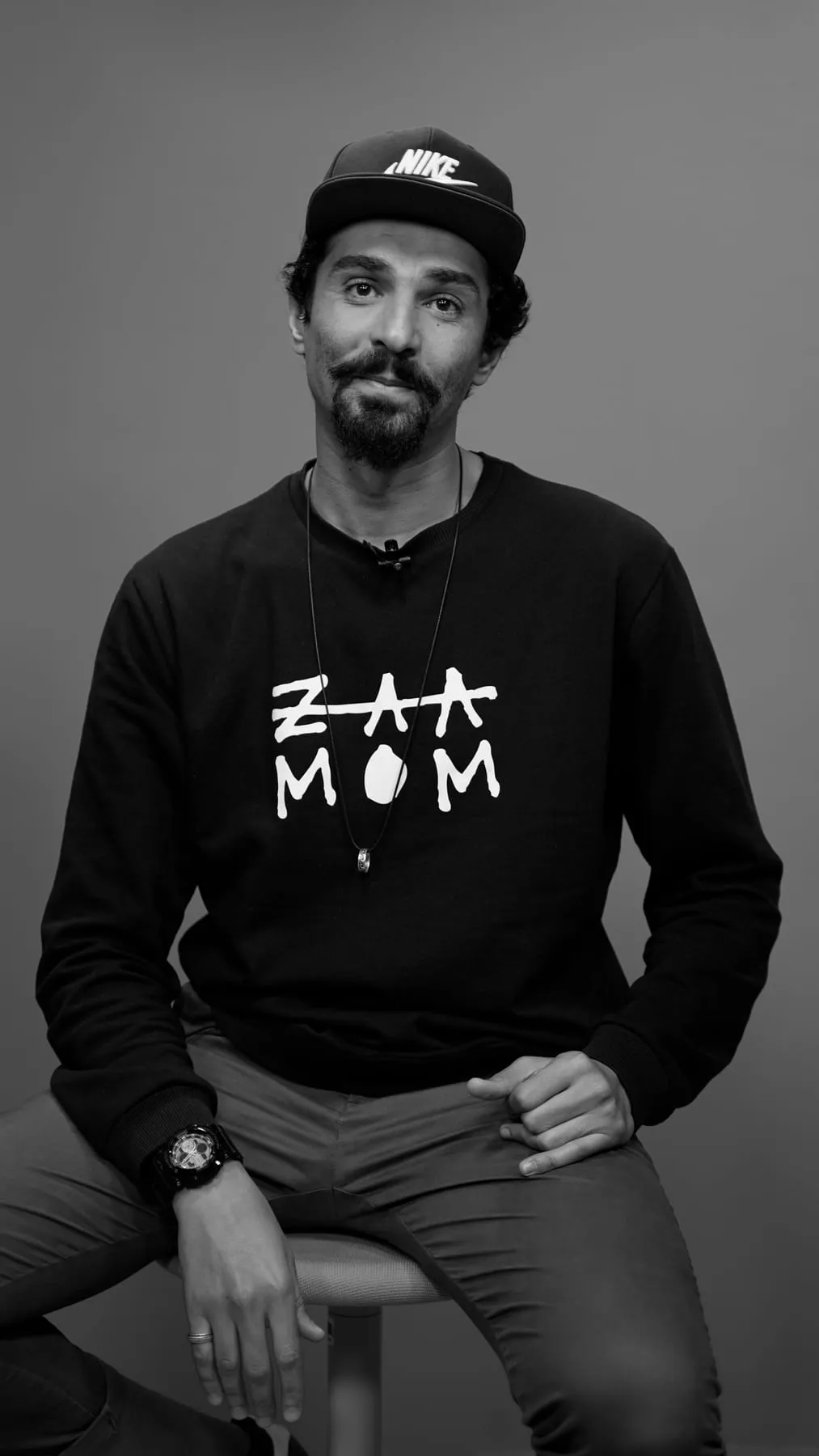 Black and white portrait of Zaamom wearing a sweatshirt with his hand-drawn ZAAMOM logo